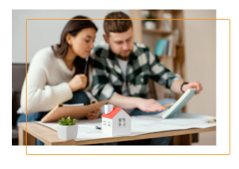 Couple reviewing documents with miniature house model